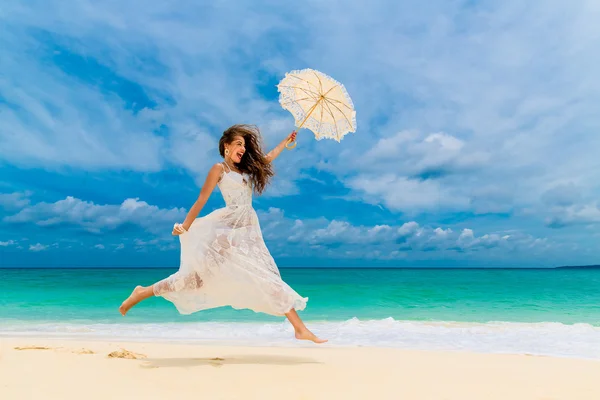 Bella giovane donna in abito bianco con ombrello su un tropicale — Foto Stock