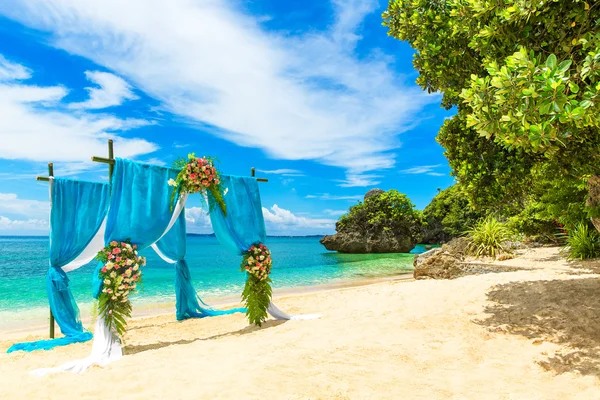Wedding ceremony on a tropical beach in blue. Arch decorated wit