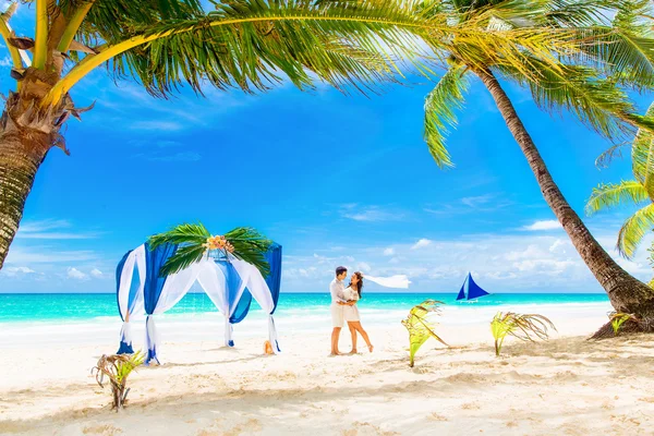 Ślub na tropikalnej plaży w kolorze niebieskim. Szczęśliwy pary młodej i br — Zdjęcie stockowe