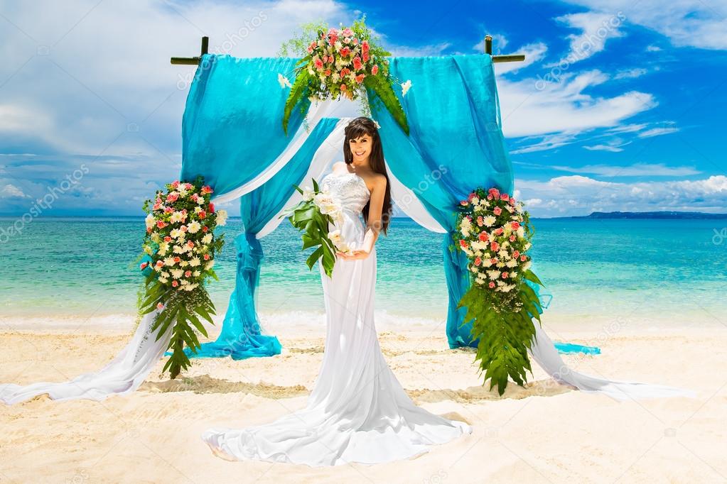 Wedding ceremony on a tropical beach. Happy bride under the wedd