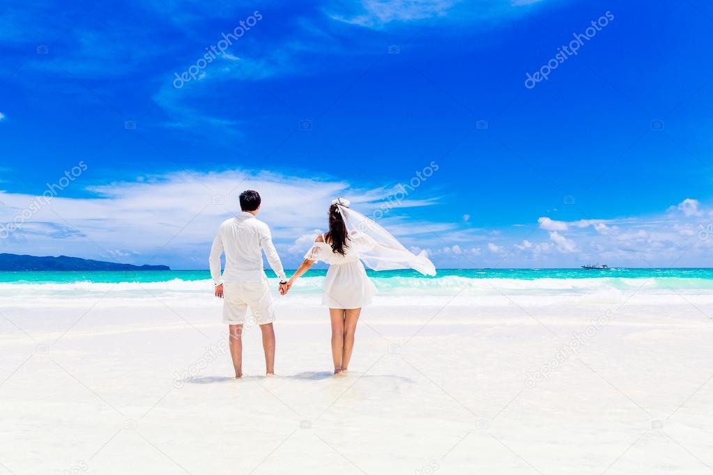 Happy groom and bride on the sandy tropical beach. Wedding and h