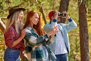 Üç Kafkasyalı arkadaş fotoğraf çeker ve dağlardaki manzarayı incelerler.