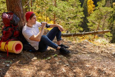 Dağlarda yürüyüş yaparken mola alan gezgin adama yan bakış