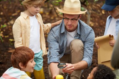 Öğretmen ve çocuklar büyüteçle limon çalışırlar.