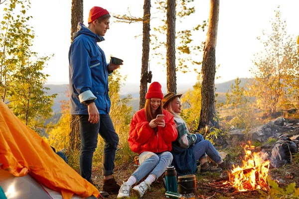 Giovani amici rilassarsi comodamente e bere tè caldo in una serata d'autunno all'aria aperta — Foto Stock