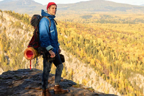 Jovem de pé com mochila no pico da montanha — Fotografia de Stock