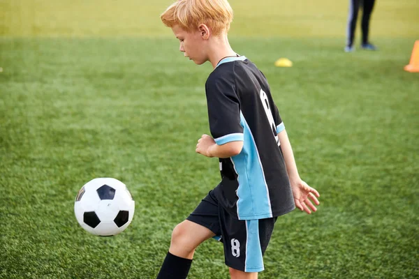 Niño pequeño entrenando con pelota solo en el estadio —  Fotos de Stock