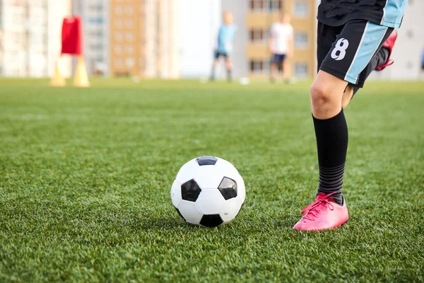 Garoto chutando bola de futebol no campo de esportes — Fotografia de Stock