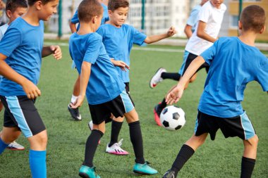Genç okul çocukları bir stadyumda futbol oynuyorlar.