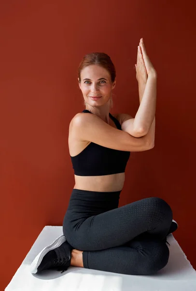 Spor salonundaki kadın kutunun üzerinde otururken yoga egzersizleri yapıyor. — Stok fotoğraf
