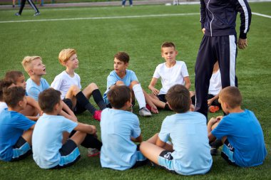 Arkadaş canlısı çocuklar futbol müsabakalarında antrenörleriyle dinleniyorlar.