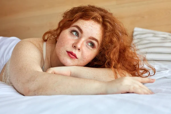 Pelirroja gordita mujer en lencería se encuentra en la cama, descansar —  Fotos de Stock