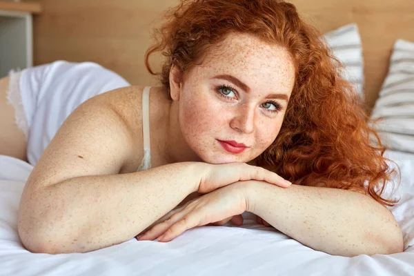 red haired chubby woman in lingerie lies on bed, have rest