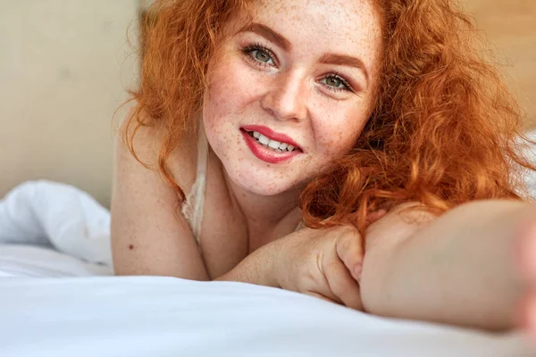Close-up portrait of curly freckled woman taking photo of herself — Stock Photo, Image