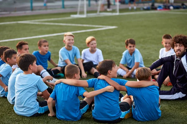 우정적 인 아이들은 미식축구 경기중에 트레이너와 휴식을 취한다. — 스톡 사진