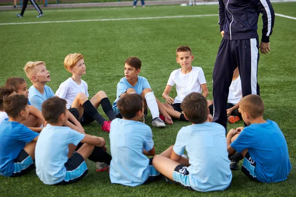 Enfants amicaux garçons ont repos avec entraîneur pendant la compétition de football — Photo