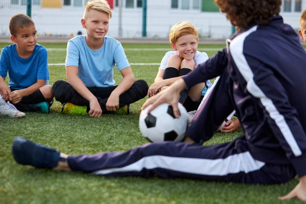 Friendly kid boys have rest with trainer during football competition — Stock Photo, Image