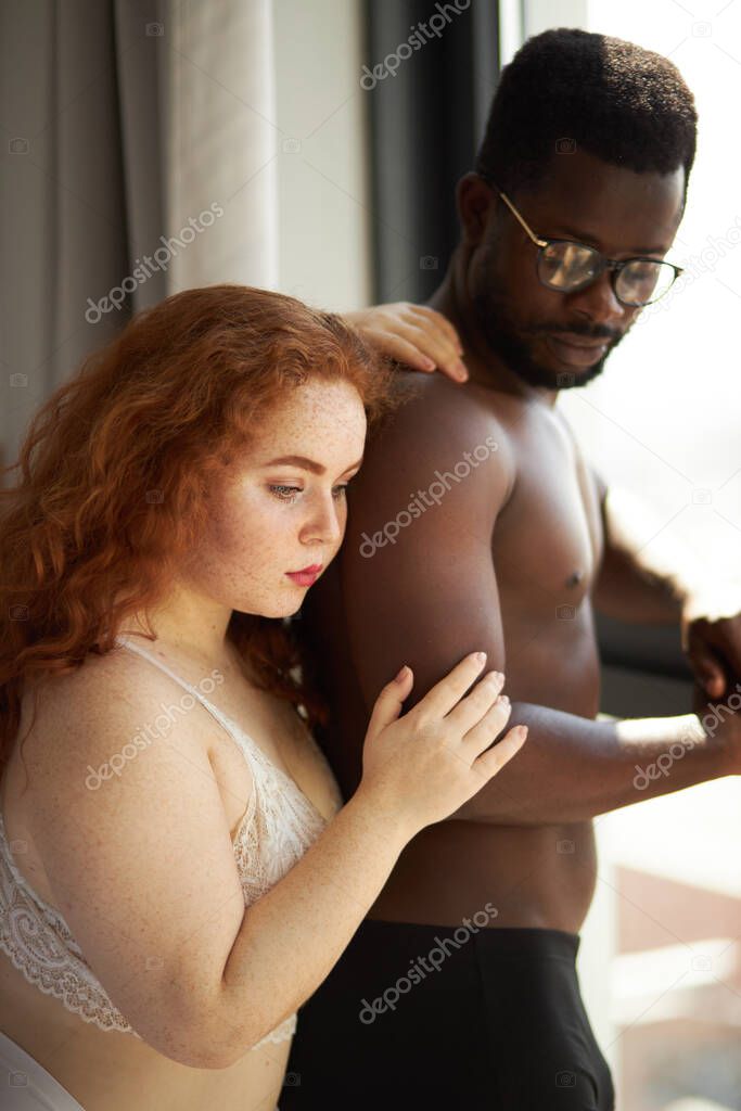 attractive fat woman with ginger hair hugs black boyfriend from back