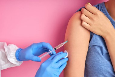 Eldivenli erkek doktorun kadın hastaya iğne yaparken yakın plan fotoğrafı.