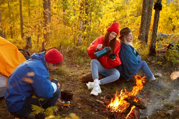 Young friends relax comfortably and drink hot tea on an autumn evening in the open air — Stock Photo, Image