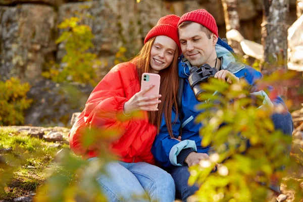 Pareja caucásica descansar en las montañas, el uso de smartphone —  Fotos de Stock