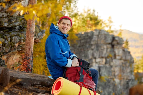 Handsome happy male is unpacking bag for travelling on mountains — Stock Photo, Image