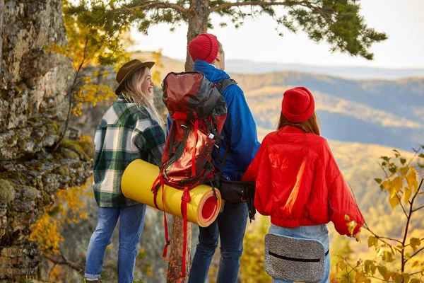 Vista trasera de tres amigos de pie en el pico de las montañas — Foto de Stock
