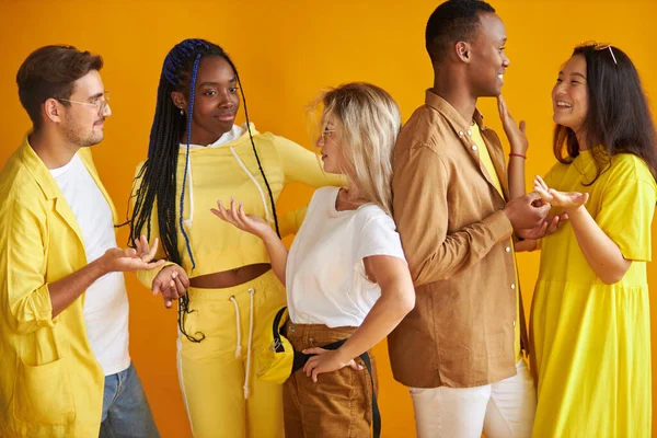 Jóvenes de raza mixta con estilo hablando, sonriendo aislado sobre fondo amarillo — Foto de Stock