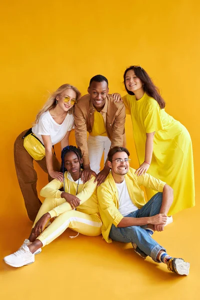 Gruppo di felici giovani uomini e donne isolati su sfondo giallo — Foto Stock