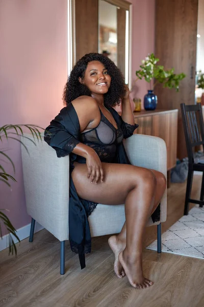 Lachende postitief afro vrouw zit op stoel genieten — Stockfoto
