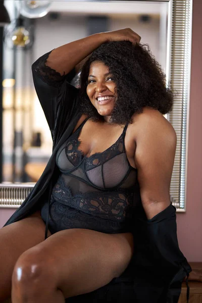 Sexy plus rozmiar kobieta siedzi na stole w bieliźnie i uśmiech — Zdjęcie stockowe