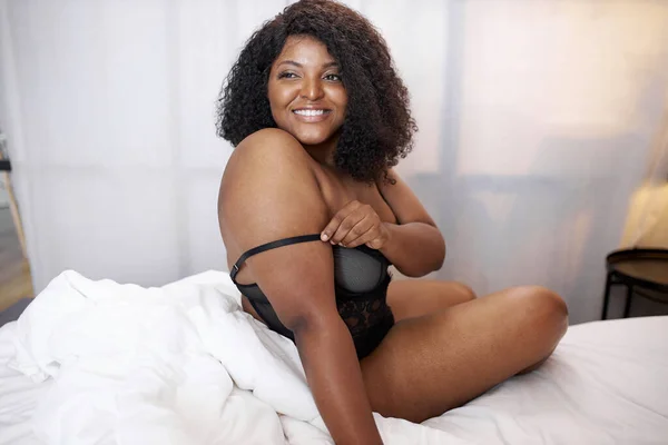 Adorable afro kobieta uśmiech siedzi na łóżku — Zdjęcie stockowe