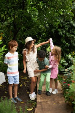 Mutlu çoklu etnik grup çocuklar eğleniyor, bahçede ya da serada yürüyor.