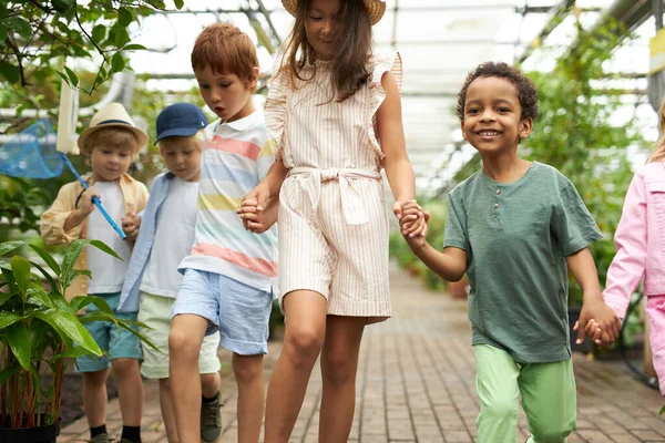 Fröhliche multiethnische Gruppe von Kindern haben Spaß, spazieren im Garten oder Gewächshaus — Stockfoto