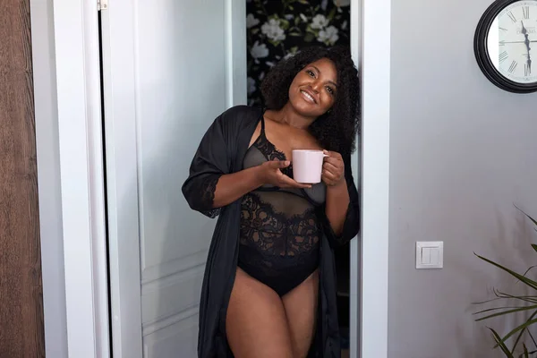 Atrakcyjne pulchne czarny kobieta wejść pokój trzymając filiżankę kawy — Zdjęcie stockowe