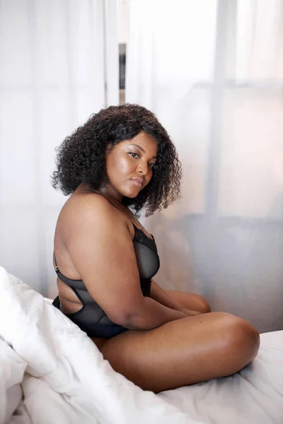 Fyllig afrikansk kvinna i underkläder sitter på sängen på morgonen — Stockfoto