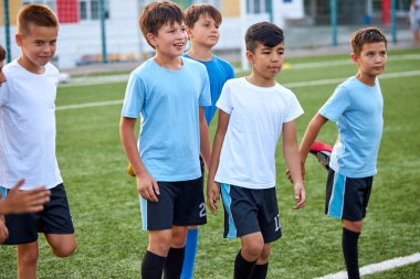 Bir grup beyaz çocuk futbol maçından önce bacak esnetiyorlar.