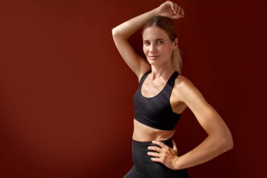 Kısa tişörtlü, kırmızı arka planda poz veren ince beyaz kadın.