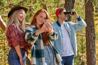 Üç Kafkasyalı arkadaş fotoğraf çeker ve dağlardaki manzarayı incelerler.