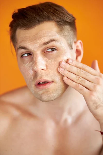 good-looking caucasian man cares for his skin, moisturizes it