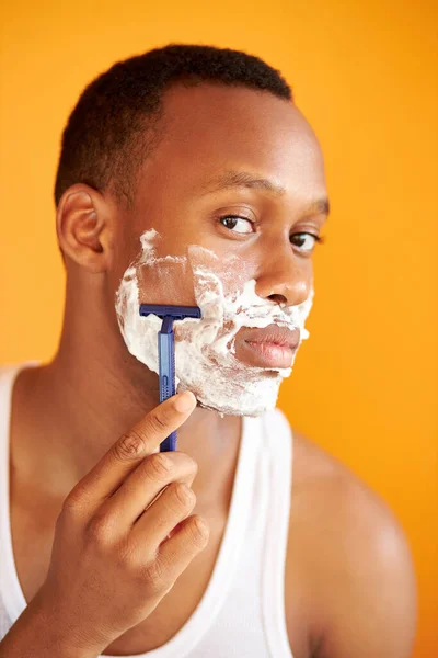 Afro américain sur fond jaune en mousse rasage avec un rasoir, portrait. — Photo