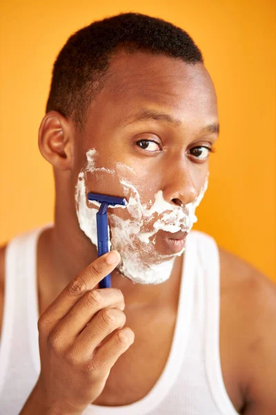 Afro américain sur fond jaune en mousse rasage avec un rasoir, portrait. — Photo