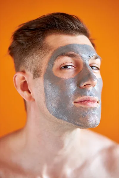 Joven guapo recibiendo tratamientos de spa, posando ante la cámara sobre un fondo amarillo aislado —  Fotos de Stock