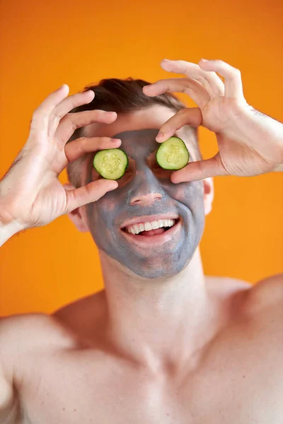 Portré vidám fehér férfi tanúja szépség arc maszk és uborka — Stock Fotó