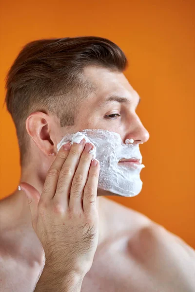 Hombre caucásico seguro de aplicar espuma afeitado después de la ducha, hacer procedimientos de belleza de la piel — Foto de Stock