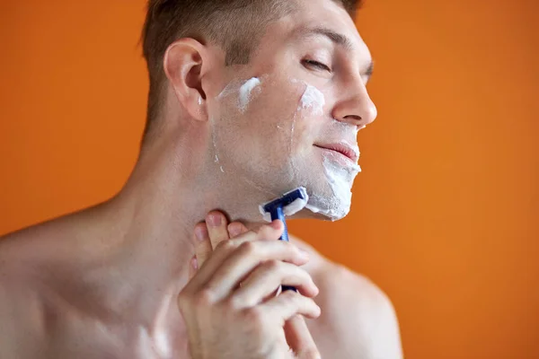 Hombre caucásico con espuma blanca en la cara, aislado sobre fondo naranja — Foto de Stock