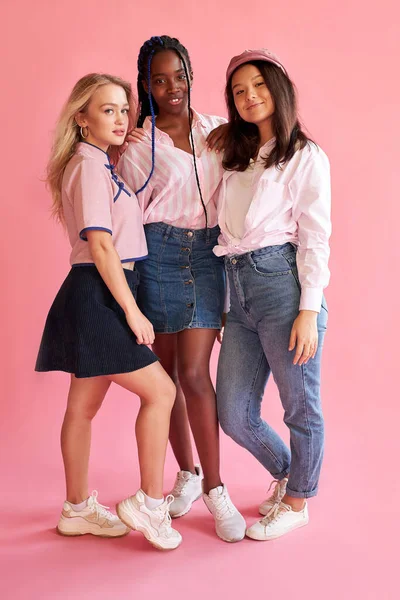 Tre giovani amiche di razza diversa in posa isolata su sfondo brillante parete rosa — Foto Stock