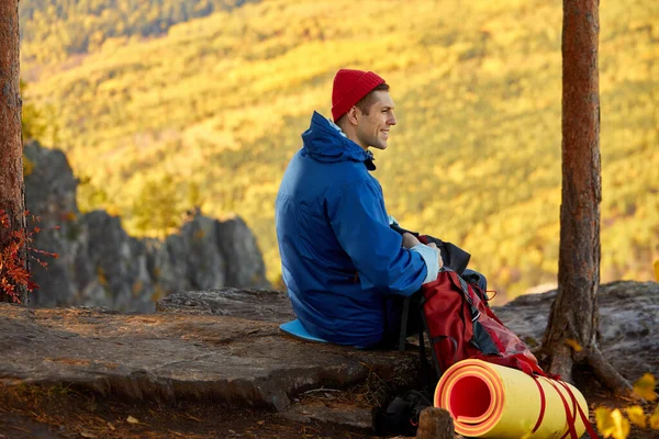 Vista laterale sulla calma turista uomo prendendo pausa sulla vetta delle montagne — Foto Stock