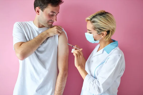 female doctor wearing mask and man patient getting injection vaccine