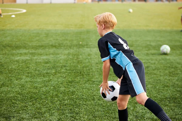 Niño pequeño entrenando con pelota solo en el estadio — Foto de Stock